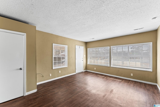 empty room with dark hardwood / wood-style floors and a textured ceiling