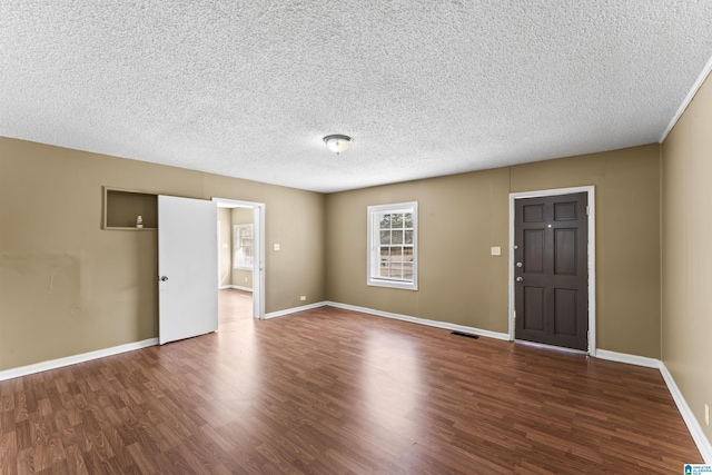 spare room with dark hardwood / wood-style floors and a textured ceiling