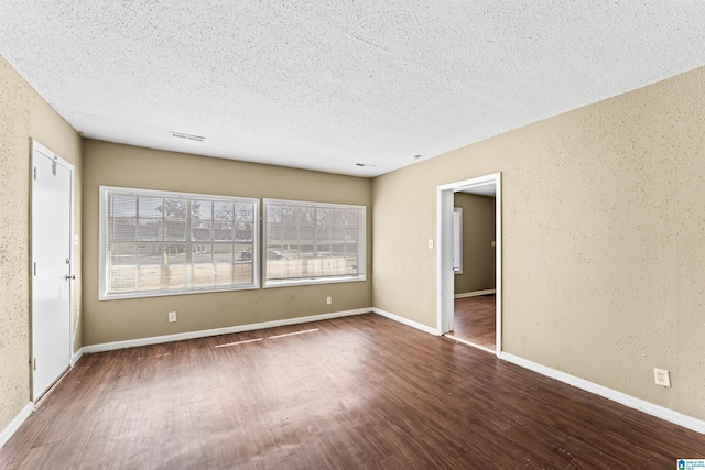 empty room featuring dark hardwood / wood-style floors and a textured ceiling