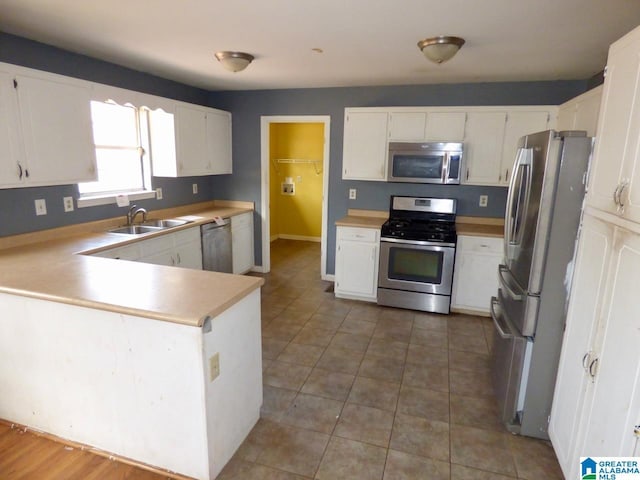 kitchen featuring appliances with stainless steel finishes, sink, white cabinets, and kitchen peninsula