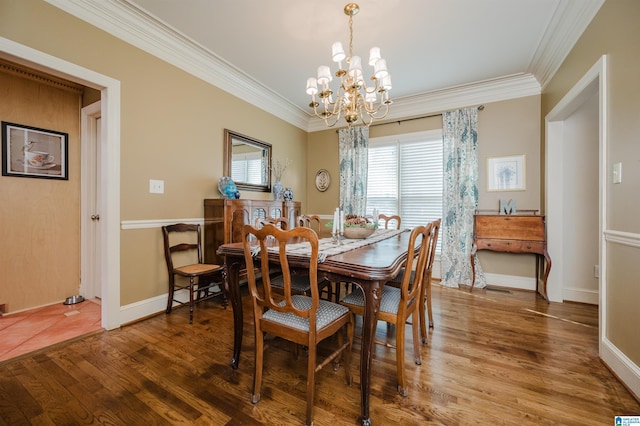 dining area with hardwood / wood-style flooring, ornamental molding, and a chandelier