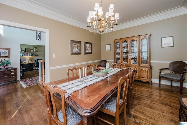 dining space with dark wood-type flooring, ornamental molding, and a chandelier