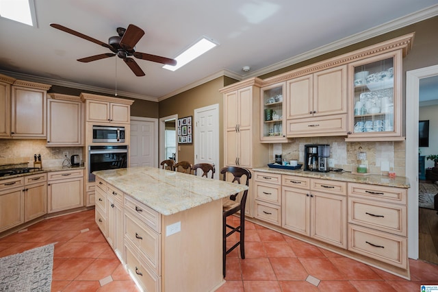 kitchen featuring light tile patterned flooring, appliances with stainless steel finishes, a breakfast bar, and a kitchen island