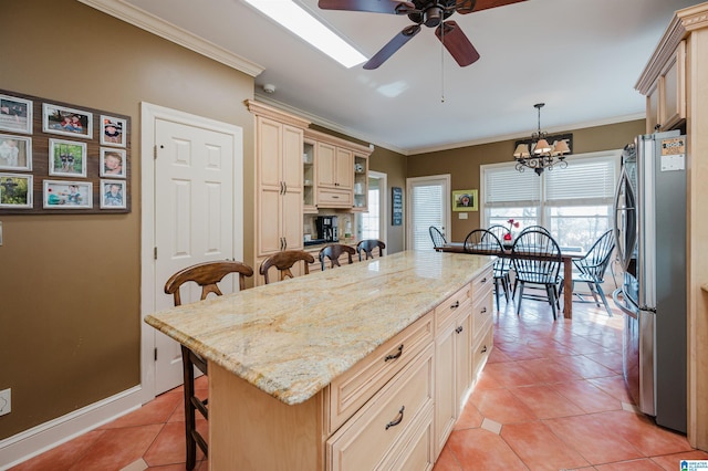 kitchen with a kitchen island, decorative light fixtures, stainless steel fridge, a kitchen bar, and crown molding