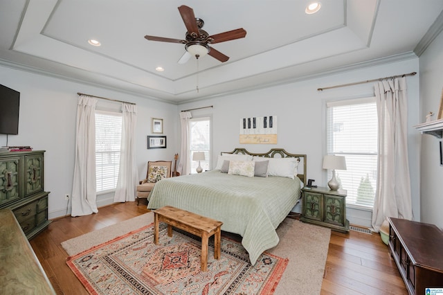 bedroom with a raised ceiling, crown molding, hardwood / wood-style flooring, and ceiling fan