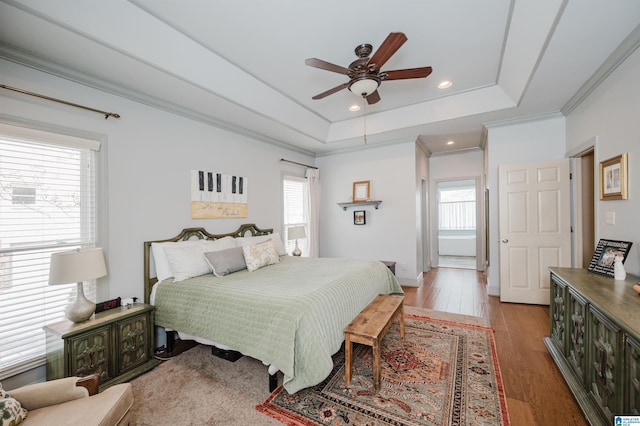 bedroom with crown molding, a tray ceiling, light hardwood / wood-style flooring, and ceiling fan