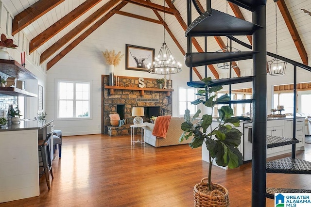 living room with beamed ceiling, wood-type flooring, a fireplace, and a notable chandelier