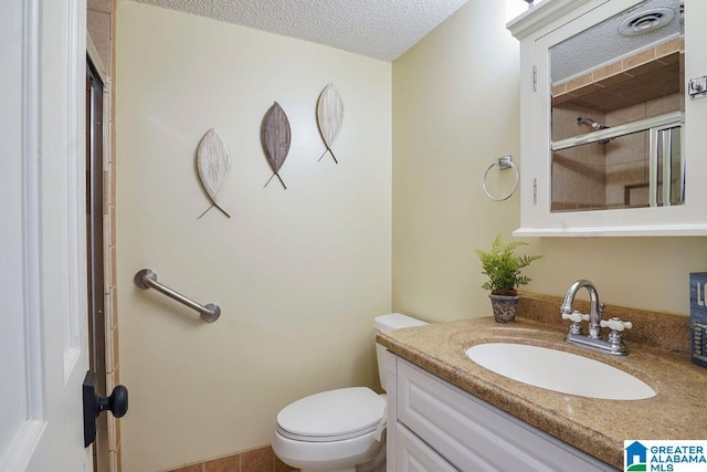 bathroom with vanity, toilet, a shower with door, and a textured ceiling