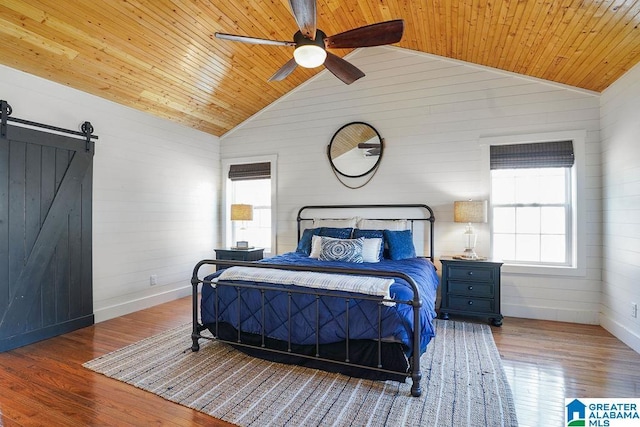 bedroom with wood ceiling, wood-type flooring, a barn door, and vaulted ceiling