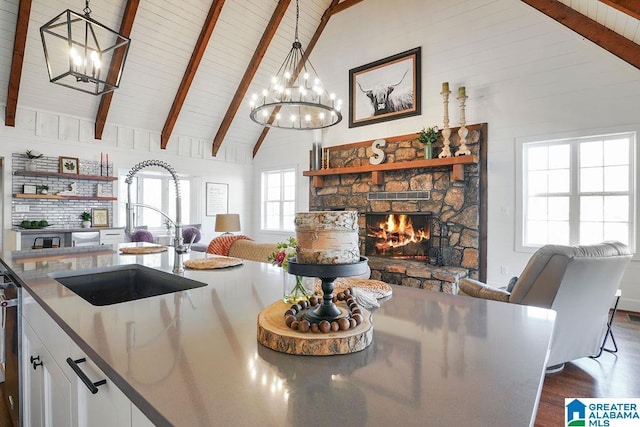 kitchen featuring hanging light fixtures, sink, white cabinets, and a fireplace