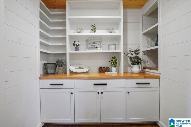 bar with wooden counters and white cabinets