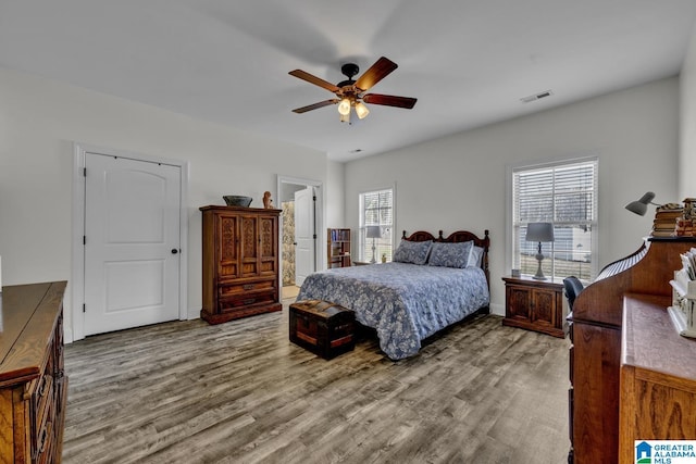 bedroom with baseboards, visible vents, ceiling fan, wood finished floors, and ensuite bathroom