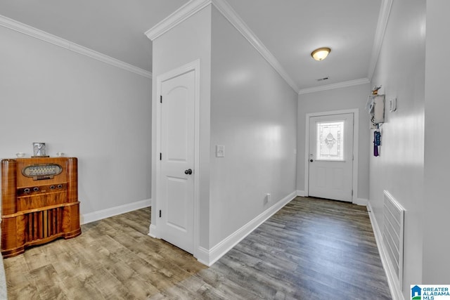 foyer with ornamental molding, visible vents, baseboards, and wood finished floors