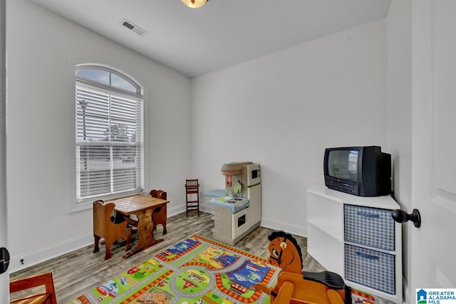 recreation room featuring wood finished floors, visible vents, and baseboards