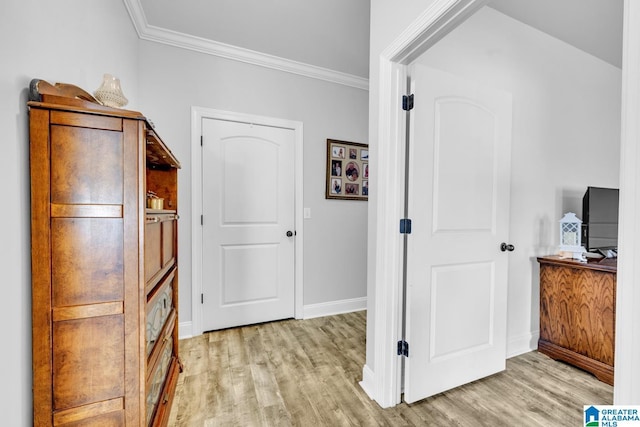 interior space featuring light wood-type flooring, crown molding, and baseboards