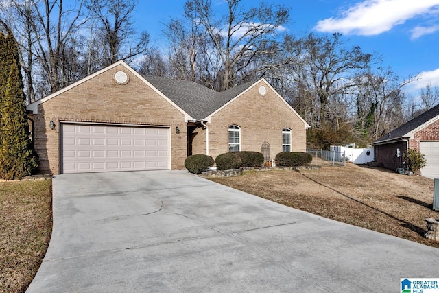 single story home featuring concrete driveway, brick siding, fence, and an attached garage