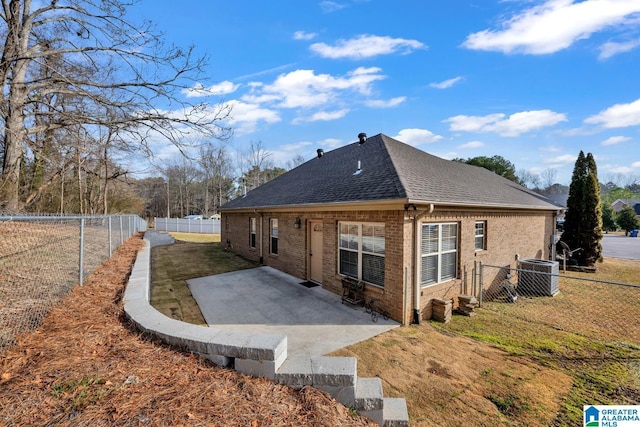 view of home's exterior featuring a shingled roof, a fenced backyard, cooling unit, a patio area, and brick siding