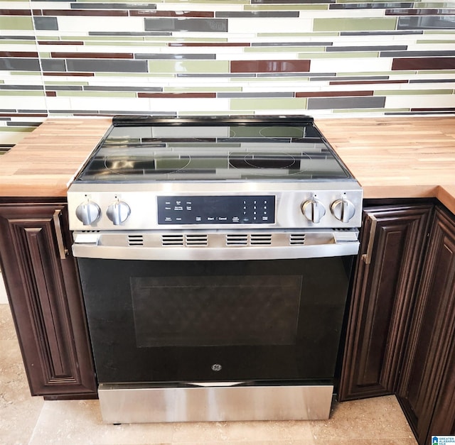 interior details featuring tasteful backsplash, wooden counters, stainless steel electric stove, and dark brown cabinets