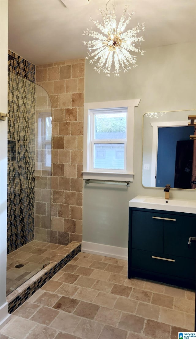 bathroom with vanity, a tile shower, and a notable chandelier