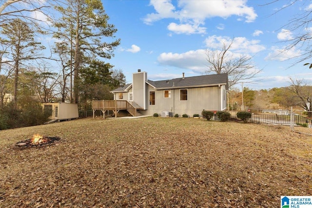 back of property featuring a storage shed, a deck, and a fire pit