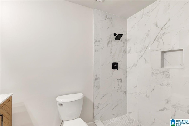 bathroom with vanity, tiled shower, and toilet