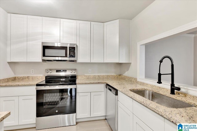 kitchen featuring light stone countertops, white cabinetry, appliances with stainless steel finishes, and sink