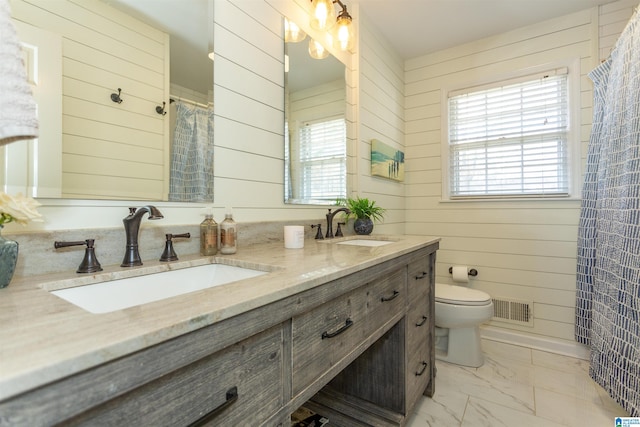 bathroom featuring vanity, toilet, and wood walls