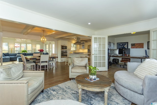 living room featuring wood-type flooring, ornamental molding, and beam ceiling