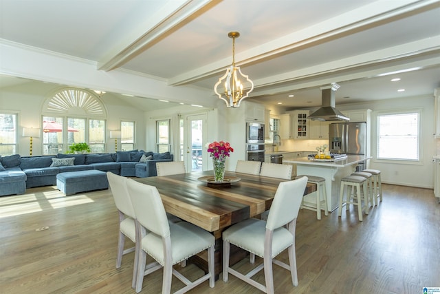 dining area featuring sink, an inviting chandelier, beam ceiling, and light hardwood / wood-style floors