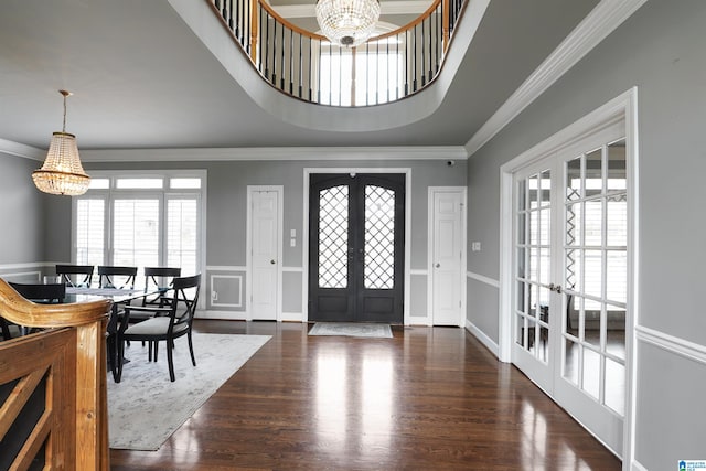 entrance foyer with ornamental molding, dark hardwood / wood-style floors, an inviting chandelier, and french doors