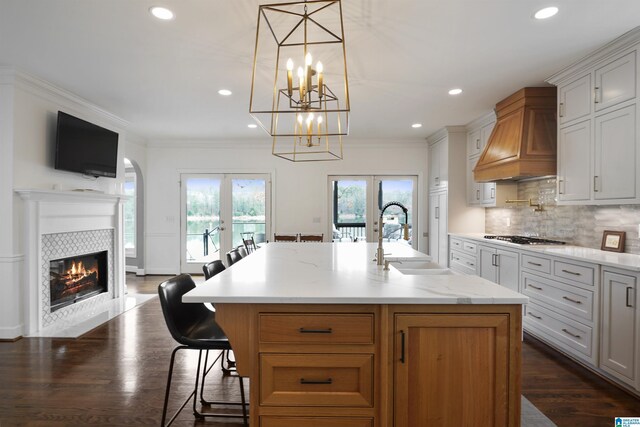 kitchen featuring white cabinetry, a kitchen breakfast bar, a spacious island, custom exhaust hood, and french doors