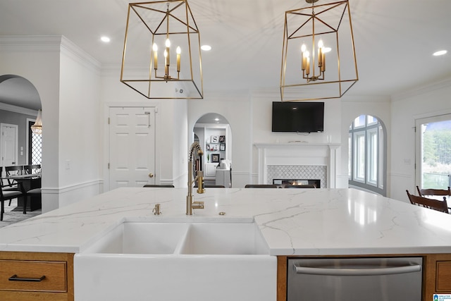 kitchen with hanging light fixtures, ornamental molding, sink, and a kitchen island with sink