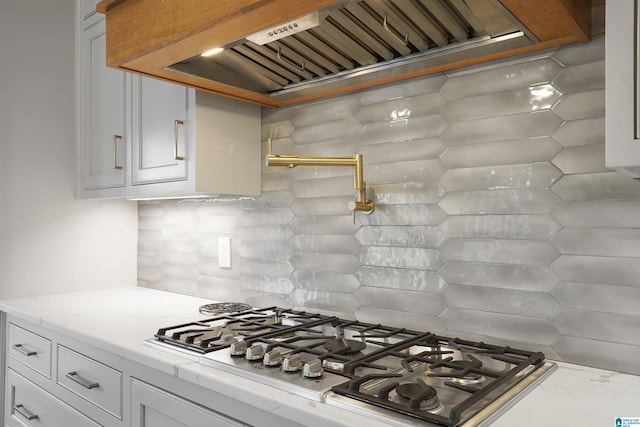 kitchen featuring stainless steel gas stovetop, white cabinetry, custom range hood, and light stone counters