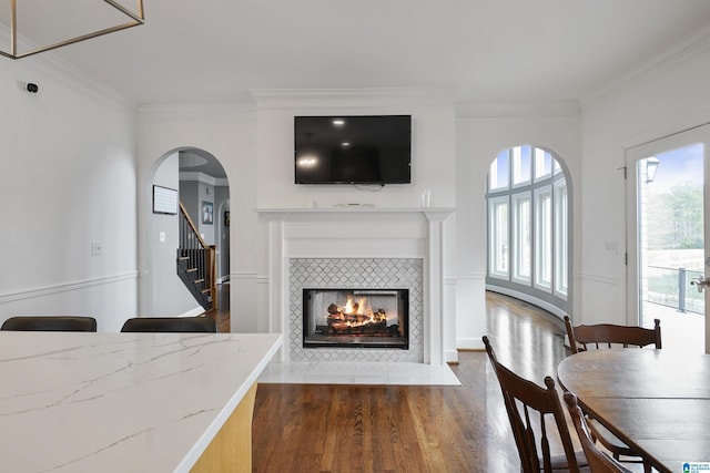 living room with a tiled fireplace, crown molding, and dark hardwood / wood-style floors