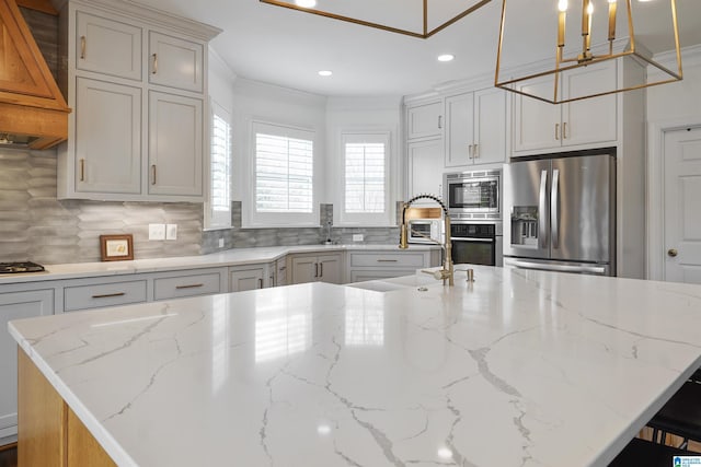 kitchen with light stone counters, appliances with stainless steel finishes, and a kitchen island with sink