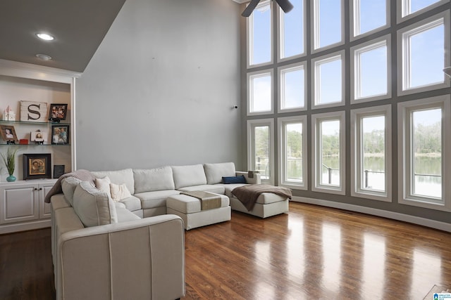 living room with ceiling fan, a towering ceiling, and wood-type flooring