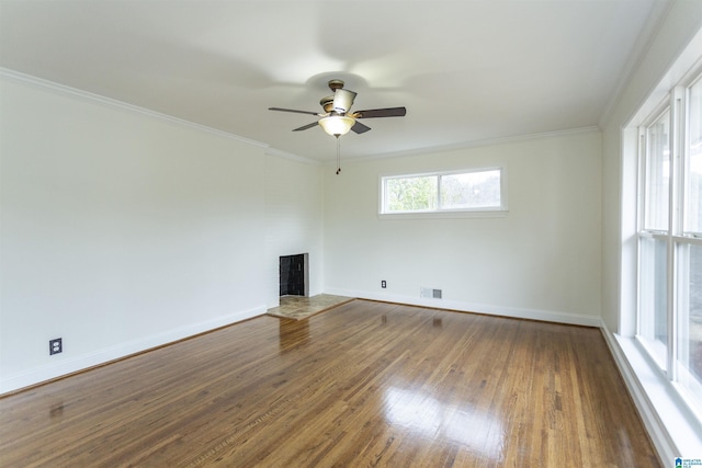 empty room featuring dark hardwood / wood-style flooring, a wealth of natural light, ornamental molding, and ceiling fan