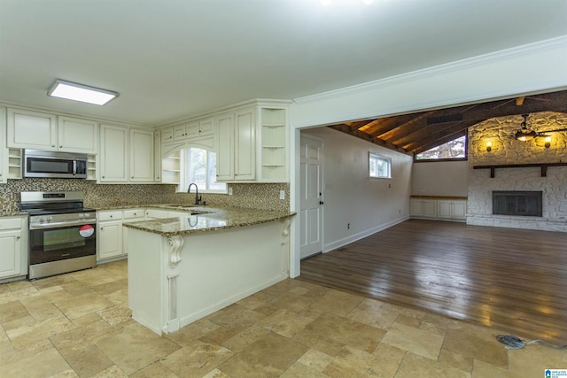 kitchen with sink, stone counters, backsplash, stainless steel appliances, and kitchen peninsula