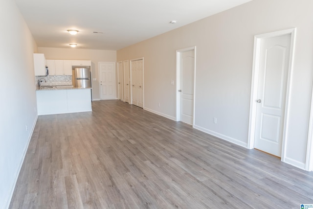 unfurnished living room with sink and light hardwood / wood-style flooring