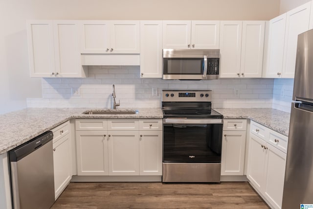 kitchen featuring sink, white cabinetry, stainless steel appliances, dark hardwood / wood-style floors, and light stone countertops