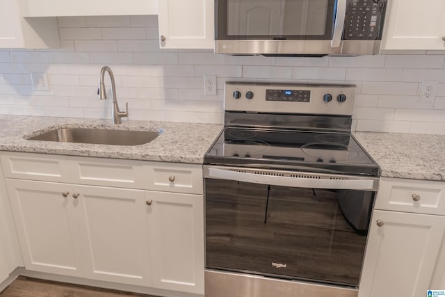 kitchen featuring white cabinetry, sink, light stone counters, and appliances with stainless steel finishes