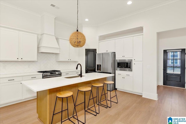 kitchen with white cabinetry, appliances with stainless steel finishes, sink, and a center island with sink