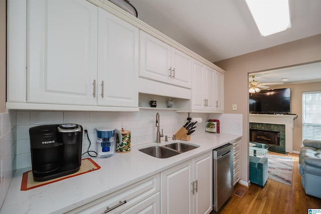 kitchen featuring sink, white cabinetry, stainless steel dishwasher, ceiling fan, and a high end fireplace