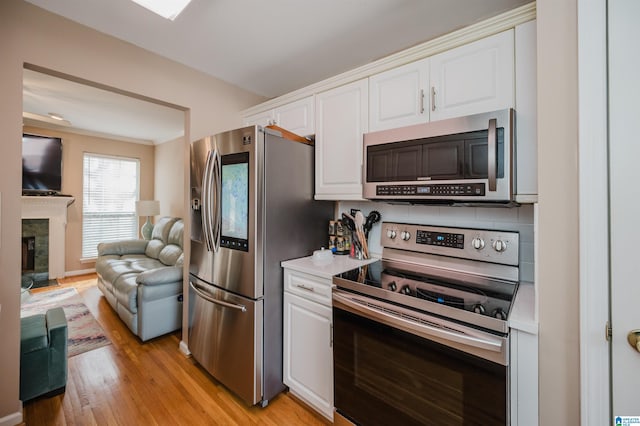 kitchen featuring white cabinetry, backsplash, light hardwood / wood-style flooring, and appliances with stainless steel finishes