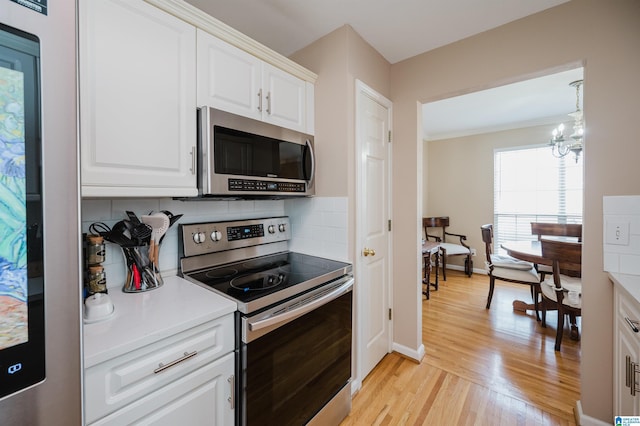 kitchen with white cabinetry, backsplash, stainless steel appliances, and light wood-type flooring