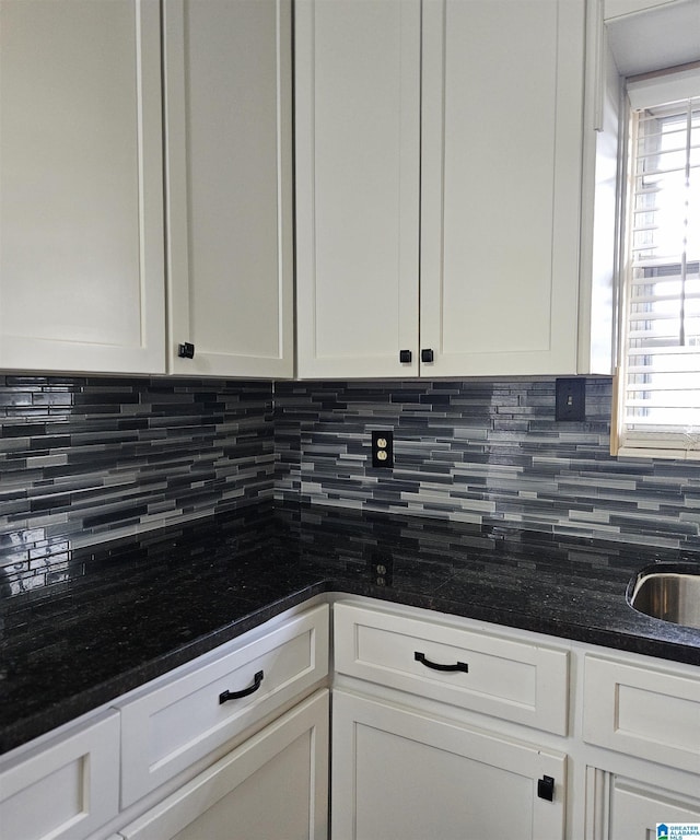 kitchen featuring dark stone countertops, backsplash, and white cabinets