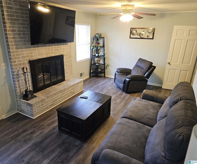 living room with crown molding, dark wood-type flooring, ceiling fan, a textured ceiling, and a brick fireplace