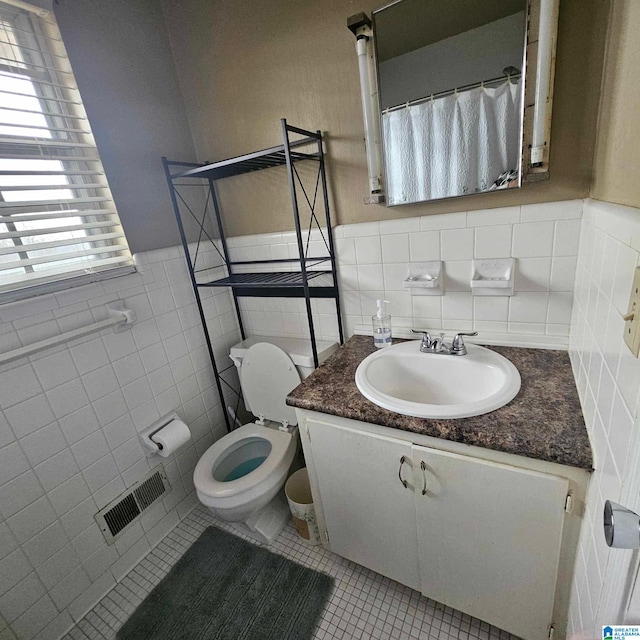 bathroom with vanity, tile patterned floors, tile walls, and toilet