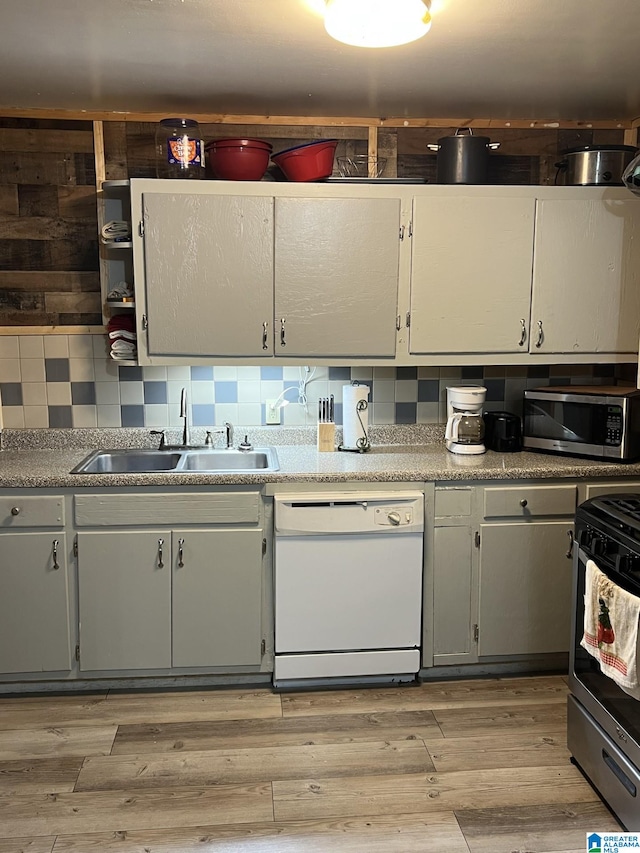 kitchen featuring stainless steel appliances, sink, light hardwood / wood-style flooring, and backsplash