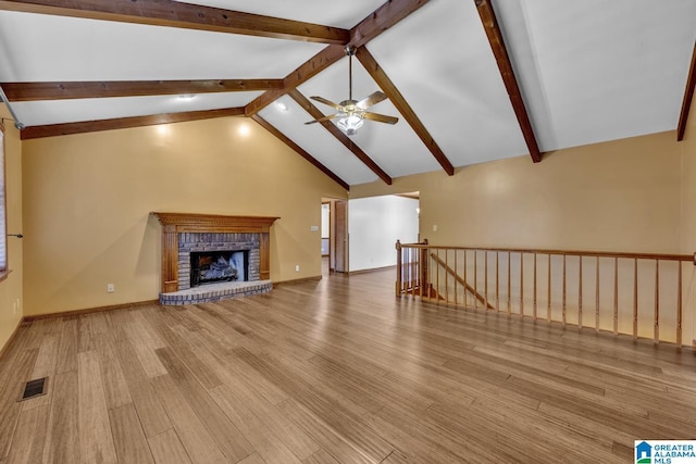 unfurnished living room featuring a fireplace, beam ceiling, and light hardwood / wood-style flooring